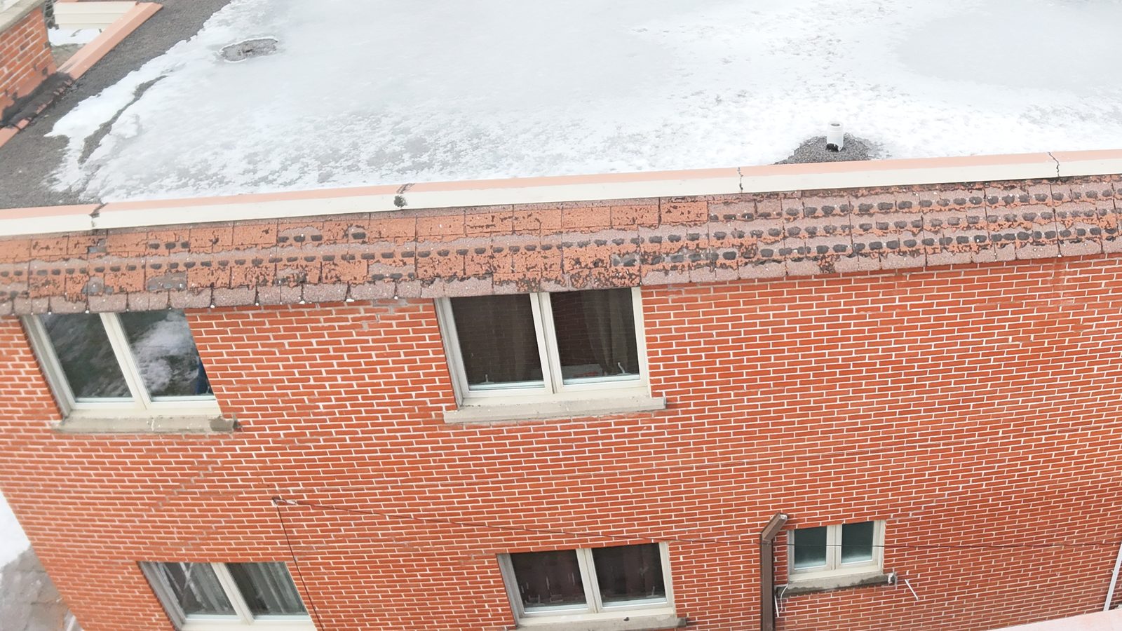 Drone view of a brick plex with a flat roof and parapet