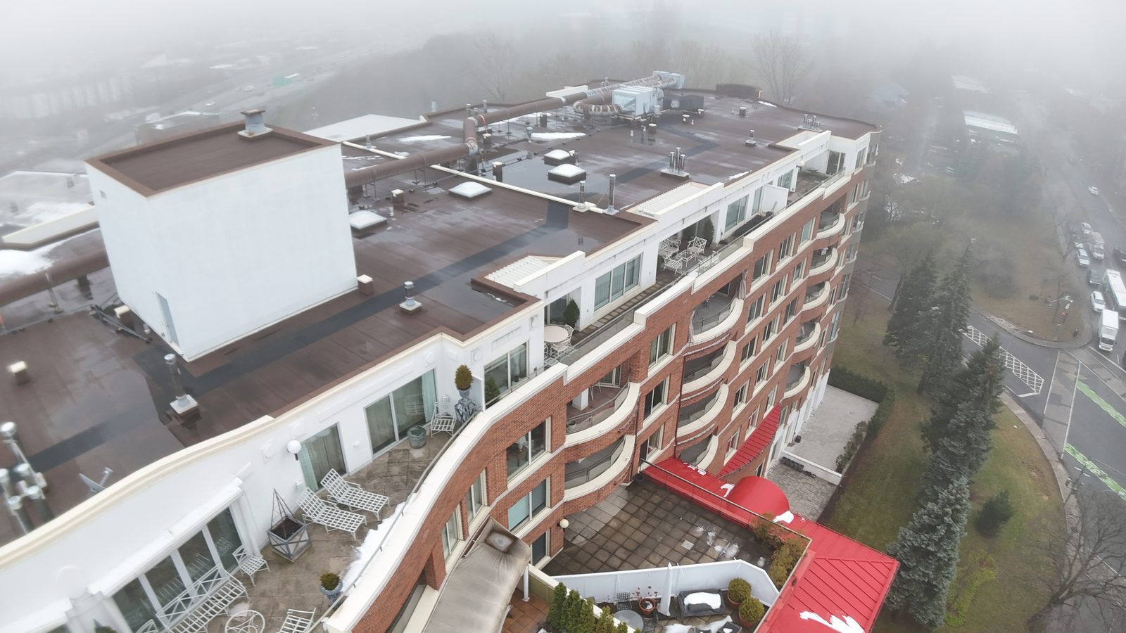 Toit plat d'un immeuble de condos en brique avec la salle mécanique et les équipements sur le toit, photographié par drone