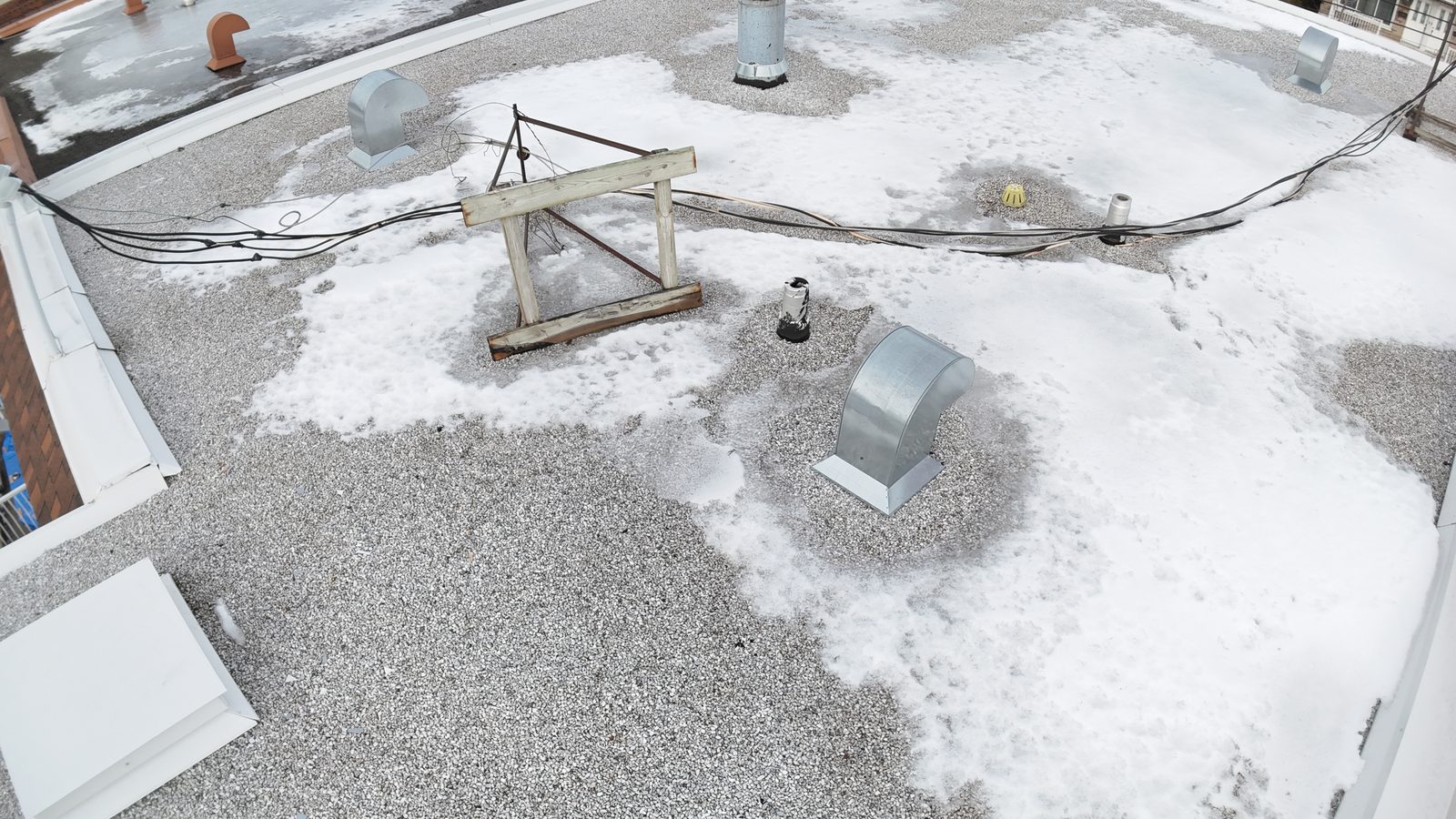 Toit plat en gravier d'un plex avec évents et trappe d'accès, photographié par drone lors d'une inspection